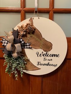 a welcome sign hanging on a door with a horse's head in the center