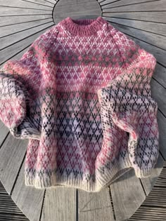 a pink and white sweater sitting on top of a wooden bench next to a piece of wood