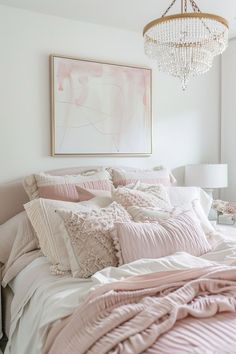 a bedroom with pink and white bedding, chandelier and pictures on the wall