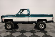 a green and white truck is parked on a checkered floor