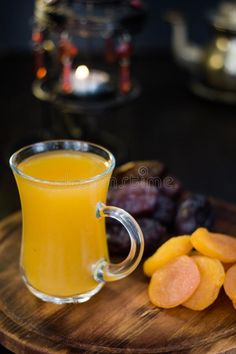 a glass mug filled with orange juice next to sliced fruit