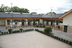 an empty parking lot in front of a building with lots of trees and bushes around it