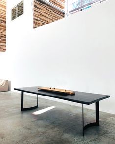 a black table sitting on top of a cement floor next to a white wall and window