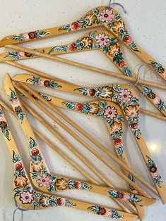 five wooden clothes pins with floral designs on them sitting on a white counter top next to a string