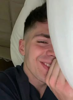 a man is smiling while hiding his face behind pillows