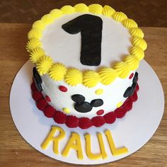 a birthday cake with the number one on it is decorated in yellow and red icing