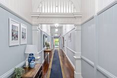 a long hallway with blue carpeting and white trim on the walls, leading to an entry way