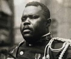 a man in uniform standing next to an american flag and looking off into the distance