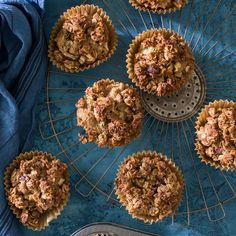 several muffins on a cooling rack with blue cloth next to it and one muffin in the middle