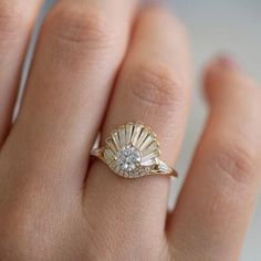 a woman's hand with a diamond ring on top of her finger and an open shell