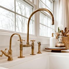 two faucets in a kitchen sink next to a window