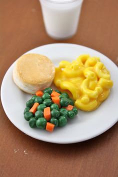 a white plate topped with macaroni and vegetables next to a cup of milk