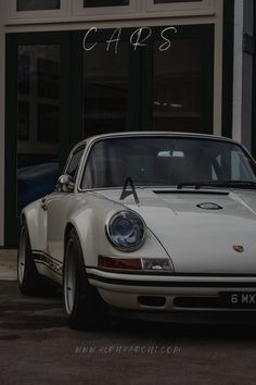 an old white porsche parked in front of a building