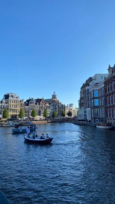 two boats traveling down a river next to tall buildings