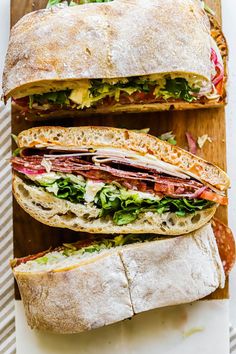 two sandwiches cut in half sitting on top of a cutting board next to each other