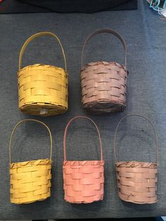 four baskets sitting on top of a table next to an orange and yellow basket with handles