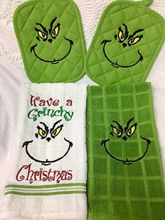 two green towels with grin face embroidered on them, one has the words have a grumpy christmas written on it