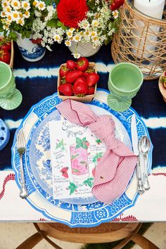 there is a blue and white plate with strawberries on it next to other plates