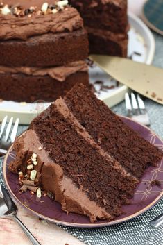 a slice of chocolate cake on a purple plate with a fork in front of it