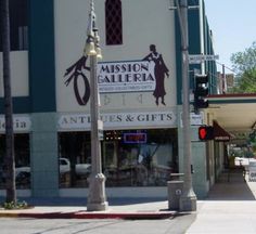 an intersection with traffic lights, street signs and storefronts on the side walk