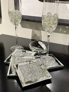 two wine glasses sitting on top of a table next to a tray with silver sequins