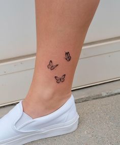 a woman's foot with three butterflies on the side of her body and one is black