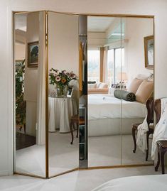 a mirrored room divider in the middle of a bedroom with a bed and table