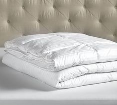 an image of a bed with white sheets and pillows on it's headboard