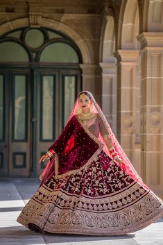 a woman in a red and gold bridal gown is posing for the camera with her hands on her hips