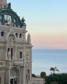 an ornate building overlooking the ocean at sunset