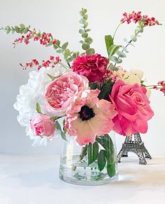 a vase filled with pink, white and red flowers next to the eiffel tower