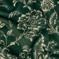 In a room full of precious treasures, become completely mesmerized with this British Imported Emerald Floral Printed Polyester Velvet. Delicate beige florals spiral across a pine-green ground with a slightly distressed pattern in its coloration. Velvety to the touch with a fuzzy plain white reverse, it features a malleable drape and no stretch. Design full-length curtains and long valances with eye-catching embroidered trim, or fashion light upholstery projects like headboards with studs, pillow Elegant Green Embroidered Fabric, Emerald Green Patterned Fabric, Elegant Green Intricate Embroidery Fabric, Green Floral Curtain Fabric, Semi-stitched Green Embroidered Fabric With Floral Design, Green Ground, Fashion Lighting, Vintage Prints, Emerald