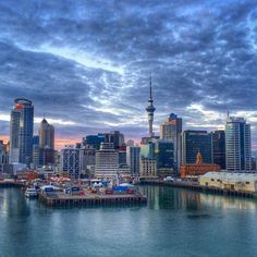 the city skyline is seen from across the water at dusk with clouds in the sky