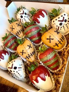 strawberries with painted faces are arranged in a box