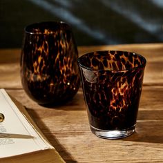 two glasses sitting on top of a wooden table next to an open book and pen