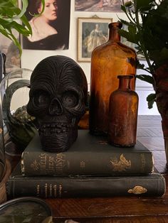 there is a skull statue sitting on top of two books next to some vases