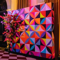 a colorful wall with flowers on it in front of a checkerboard floor and yellow curtains