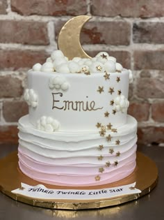 a three tiered cake decorated with stars, moon and the word emmie on it