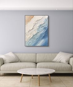 an abstract painting hangs on the wall above a white couch in a room with blue walls