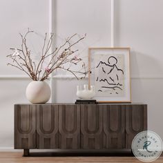 two vases sitting on top of a wooden cabinet next to a painting and plant