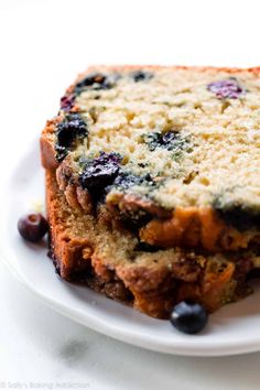 a piece of bread with blueberries on it is sitting on a plate next to a fork