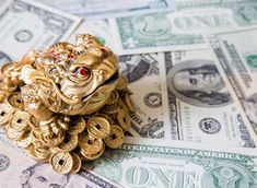 a pile of money sitting on top of each other next to a gold frog figurine