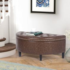 a round ottoman sitting on top of a hard wood floor next to a stair case