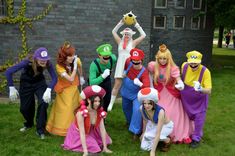 a group of people dressed in costumes posing for a photo on the grass with each other