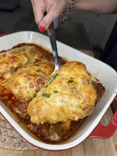 a person is cutting into some food in a casserole dish with a knife and fork