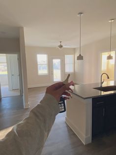 a person is holding a house key in the middle of an empty kitchen and living room