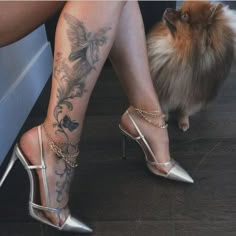 a woman's legs with tattoos on them and a small dog sitting next to her