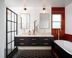 a black and white bathroom with two sinks and a bathtub in front of the mirror