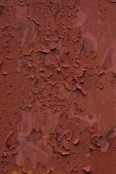 an old red wall with peeling paint on it