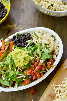 a salad with black beans, tomatoes, lettuce and avocado in a white bowl